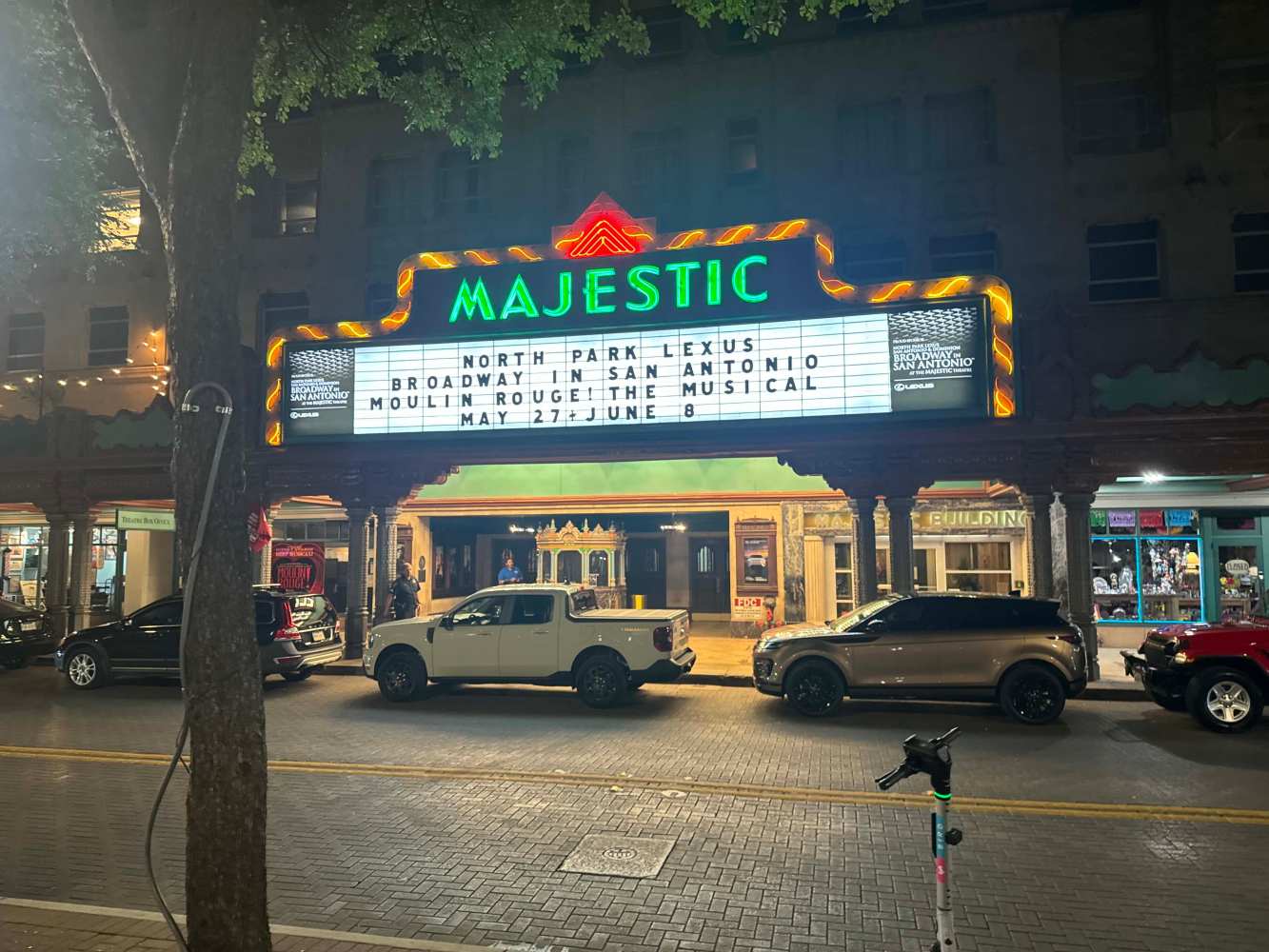 Majestic Theater neon sign at night with cars and a scooter in front, announcing Moulin Rouge musical.