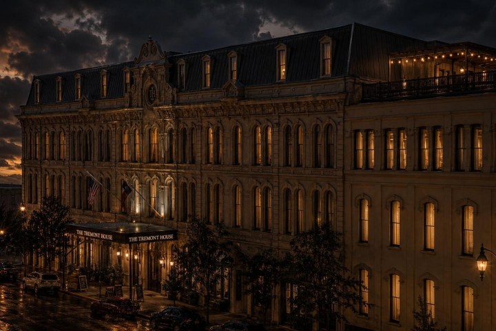 Historic hotel with lit windows under cloudy evening sky.