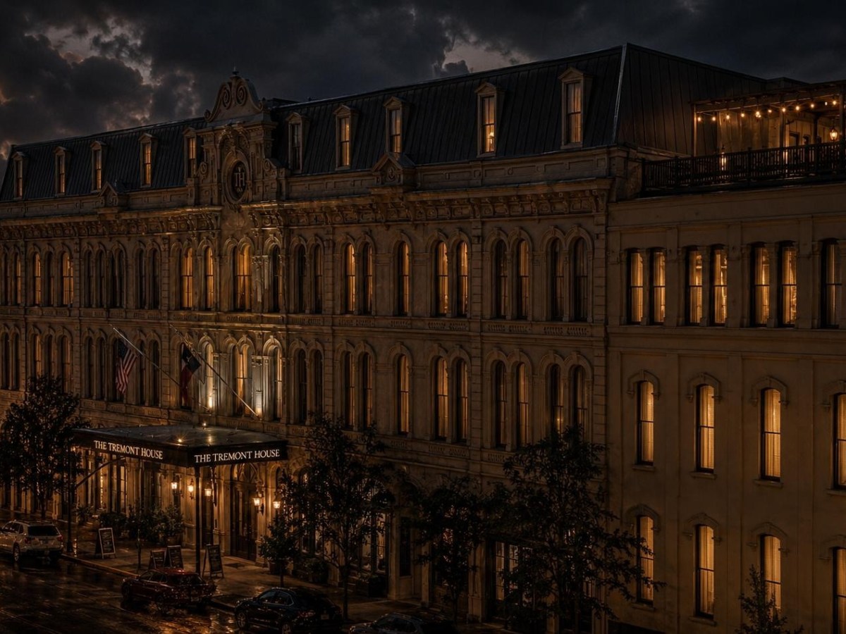Historic hotel with lit windows under cloudy evening sky.